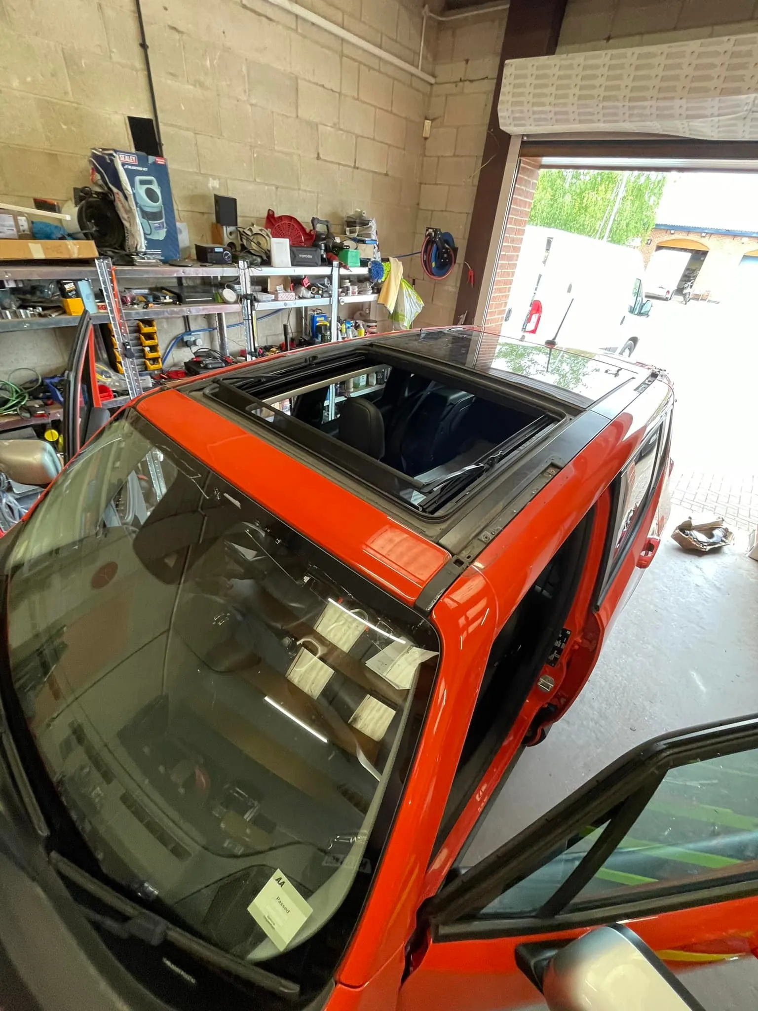 A red car parked in a garage next to other cars.