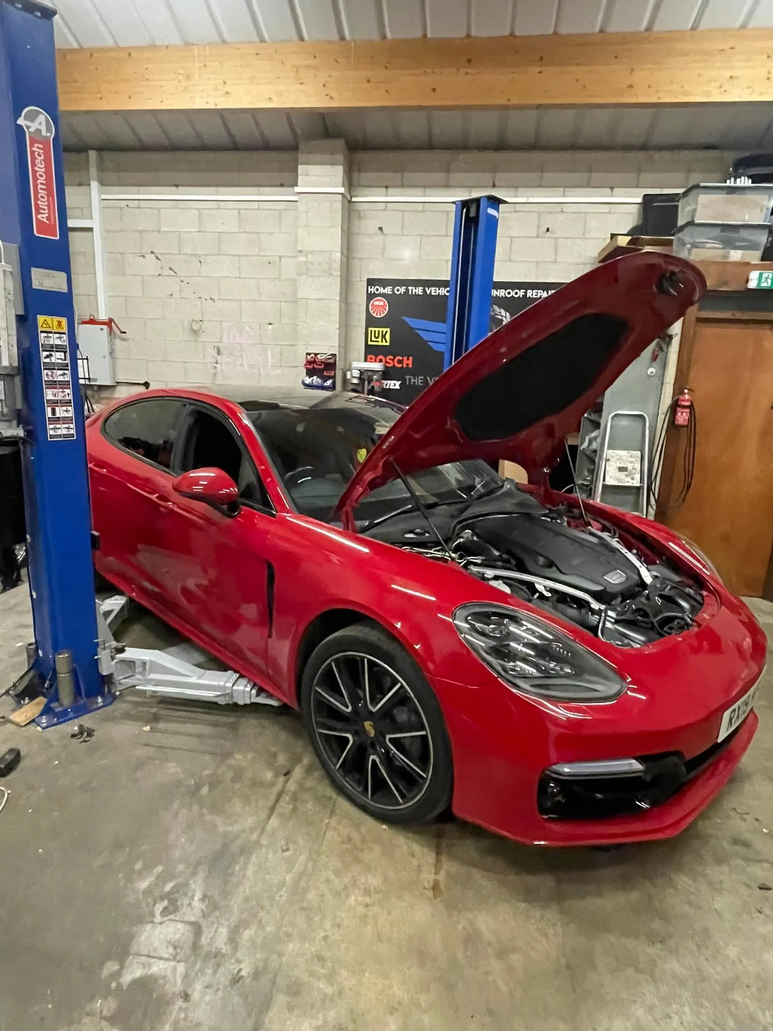 A red sports car with its hood open.